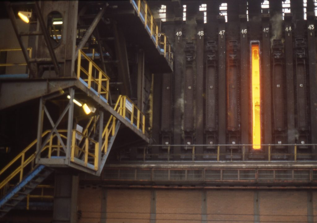 Kooksovenbatterij met een gloeiende ovendeur tussen het staalwerk