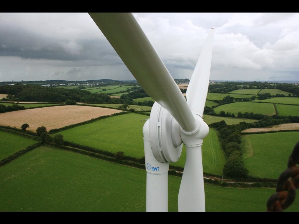 Zicht vanaf de nacelle van een EWT-turbine: rotorblad en naaf op de voorgrond, akkerland eronder.