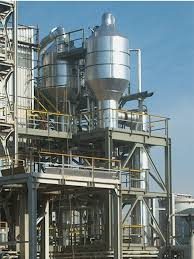 Procesinstallatie met silo, leidingwerk en bordessen tegen een blauwe lucht