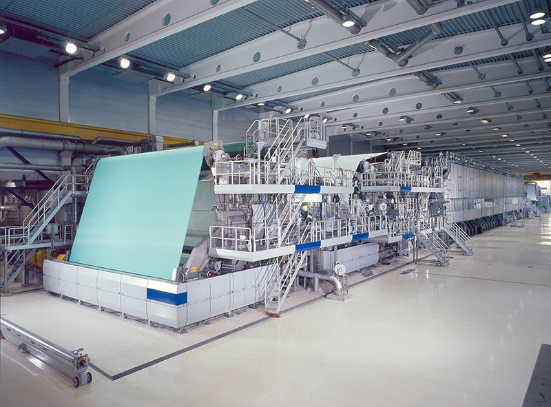 Papierfabriek met de papierbaan over de wals in de machinehal